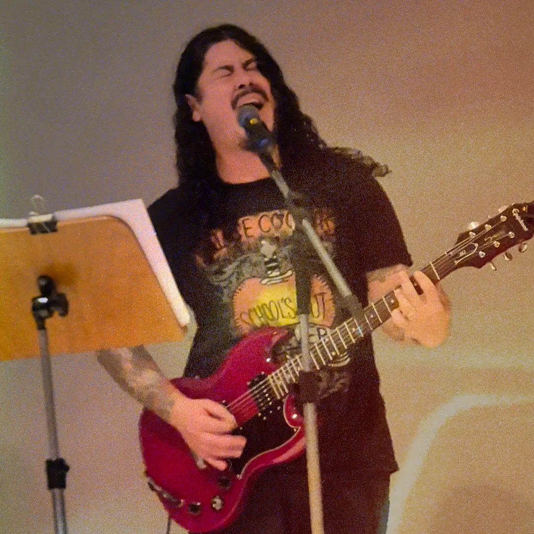 Guitarrista da ALLMEGA cantando com guitarra vermelha