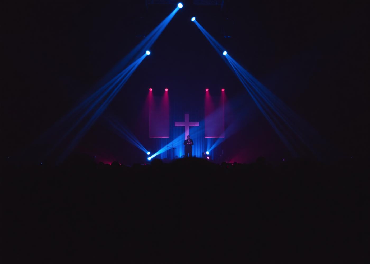 Palco de culto iluminado por feixes de luz azul durante louvor